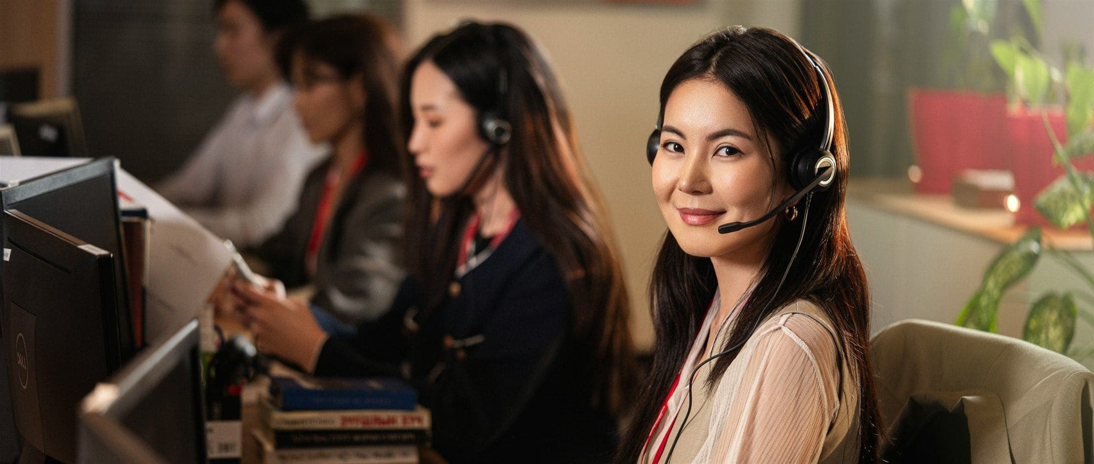 Atendente da Aurum com headset, sorrindo, cercada pela equipe